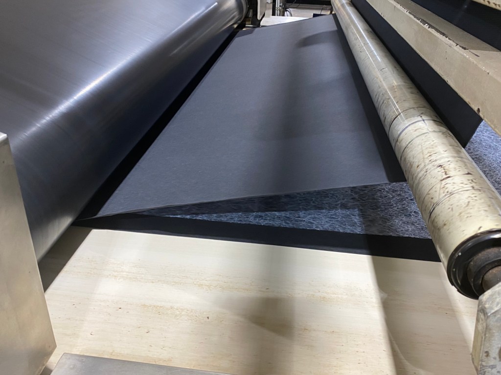 Black laminating material stretched over rollers. 